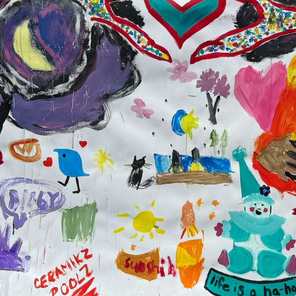 Colorful mural of playful, childlike paintings featuring hearts, animals, suns, and imaginative shapes.